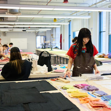 Student in a classroom completing a textile project with hand-dyed fabrics.