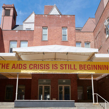 A brick building with a yellow banner that reads "The AIDS crisis is still beginning."