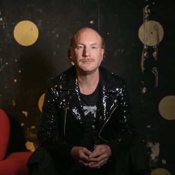 SAIC faculty member Mark Jeffery, a person with light skin tone sitting against a dark backdrop.