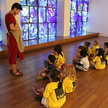 Students sit in from of the Chagall windows and listen to instructor speak