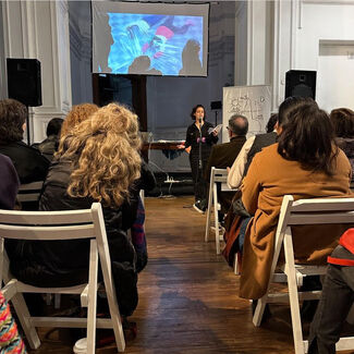 A white woman speaking into a microphone to an audience during a presentation