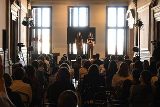 An audience watches two people standing at the front of the room