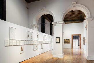 A white gallery space with archways and artwork hanging on walls