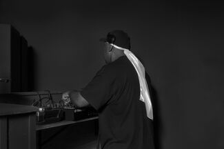 Black and white photo by Cecil McDonald, Jr. of an adult Black man DJing with his back facing the camera