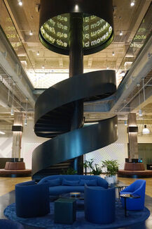 A blue couch in front of a spiral metal staircase