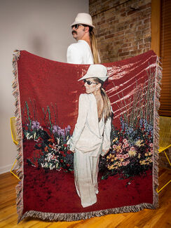 A photo of a person standing with a blanket that depicts Celine Dion in a white suit