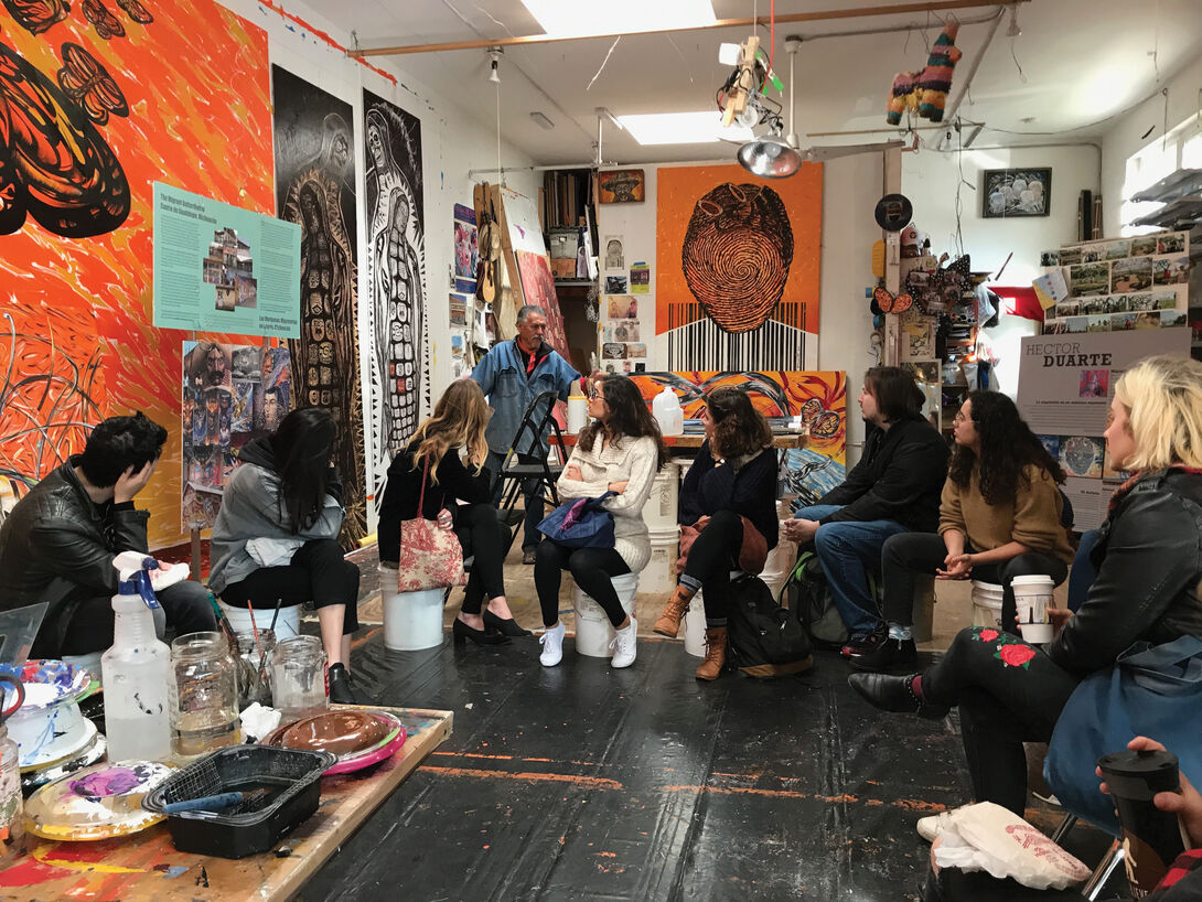 Group of students with teacher sitting among colorful art