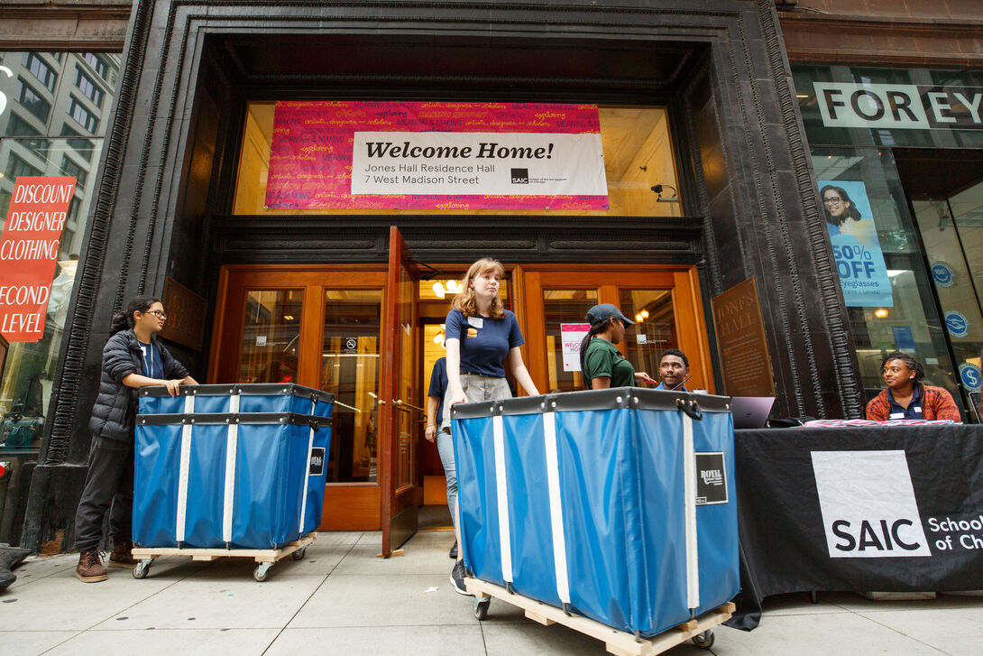 Students wheeling carts in and out of a residence hall