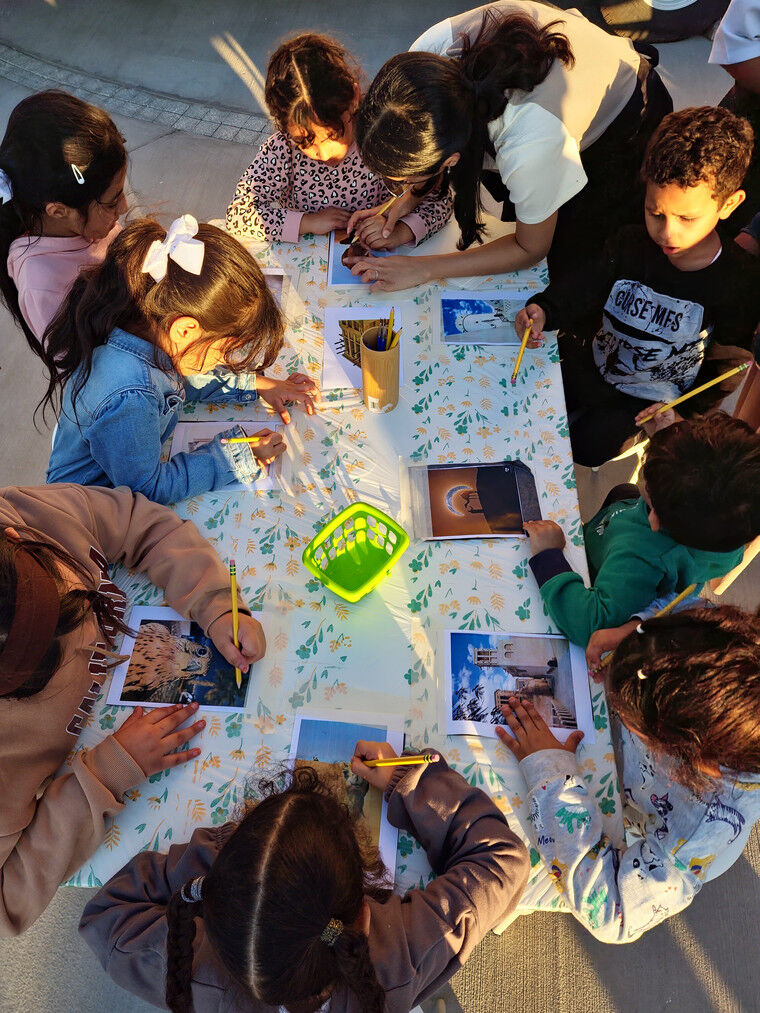 Children gathered around a table at sunset doing crafts.