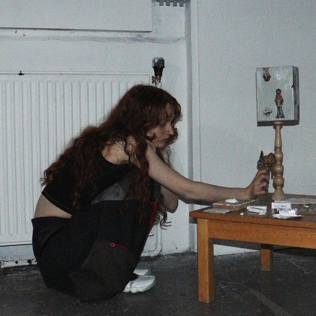 A woman kneeling in front of a table, examining something closely.