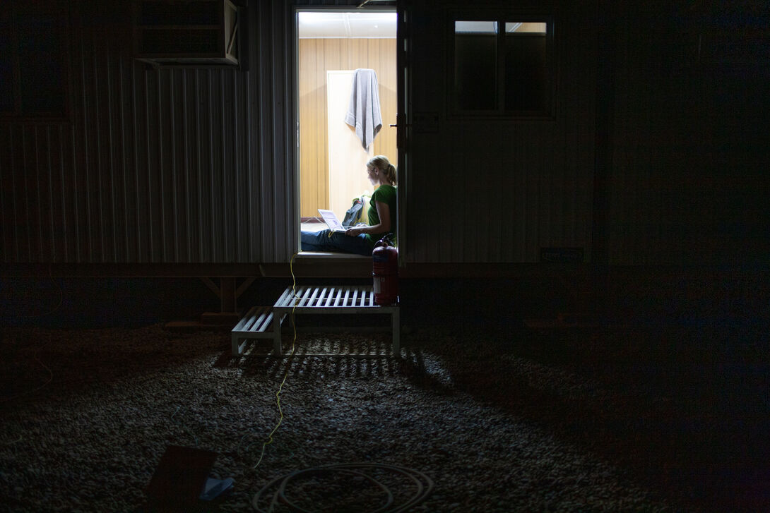 A woman sitting in a window silhouetted by the light