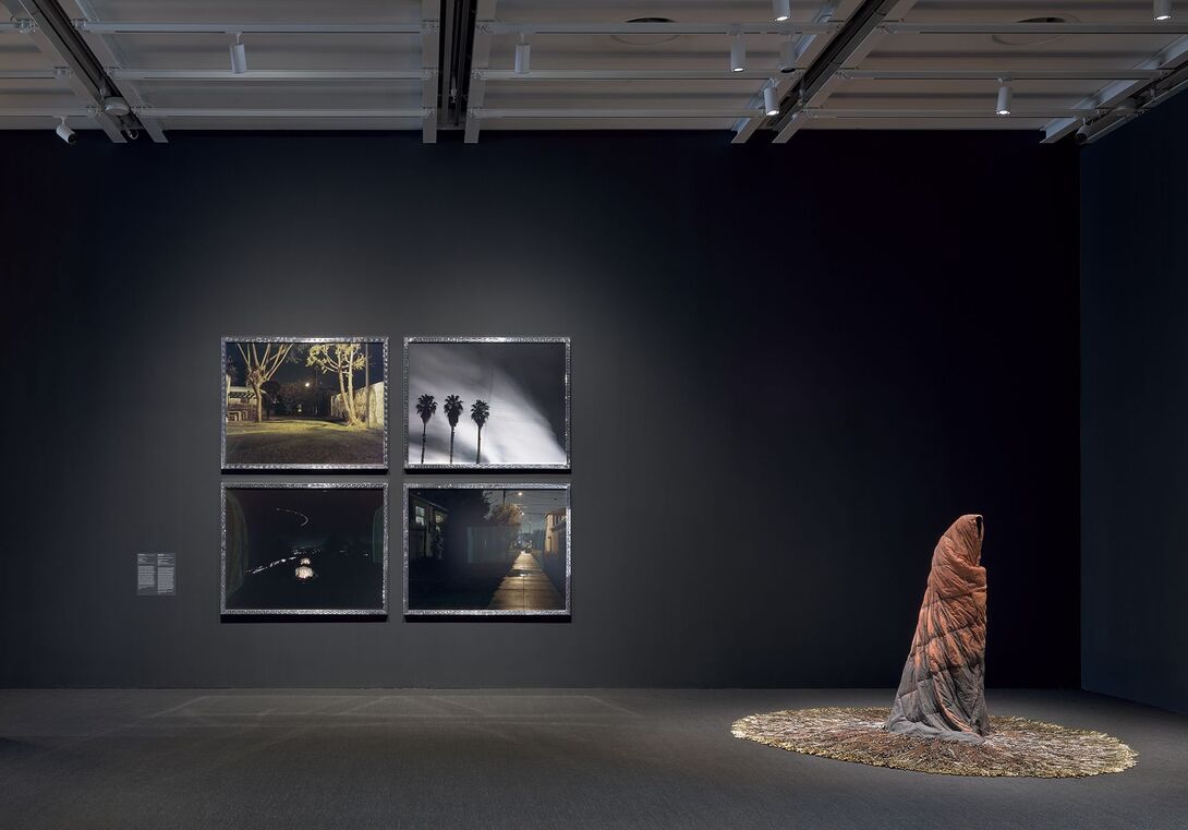 a gallery with the walls painted black, spotlight on four photographs