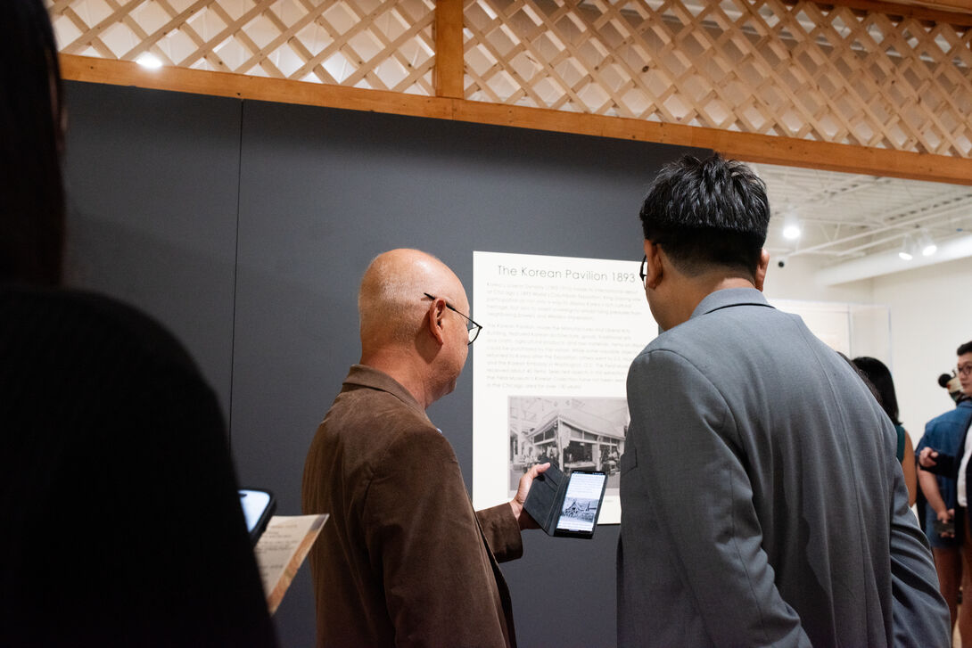 Attendants of the opening of the Symbolism exhibition standing in front of the wall and pavillion