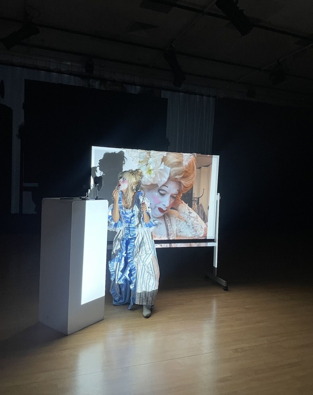 A woman wearing a dress stands before a projection screen, poised and prepared for a presentation or discussion.