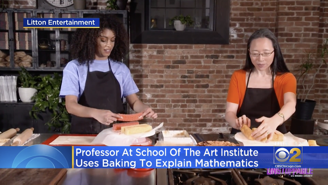 A still from a television program where two women are wearing aprons and baking together