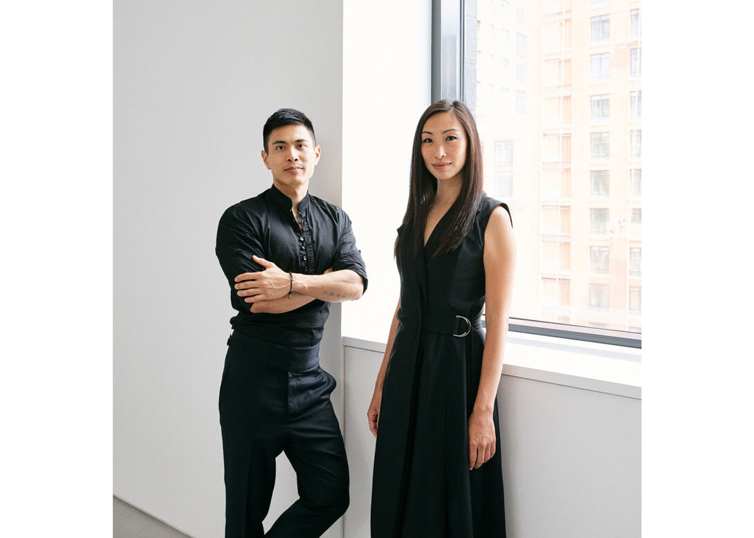 Two individuals pose in a white gallery space